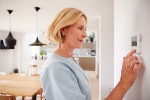 woman adjusting her thermostat of her HVAC system